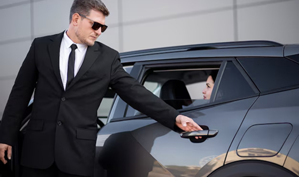 A professional chauffeur opening the car door for a passenger.